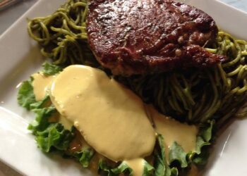Tallarines verdes acompañados de una sábana de bistec apanado y papa amarilla con crema a la huancaína